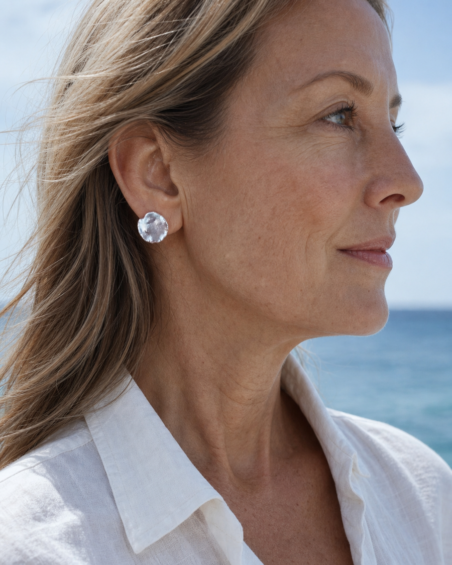 Woman wearing baroque pearl stud earrings by the sea